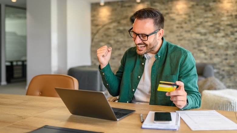 man holding credit card and looking at laptop