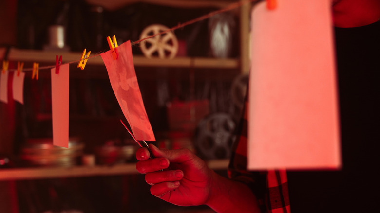 Person handles photographs hanging on line in a darkroom