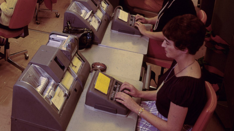Woman types using 1970s era computer equipment