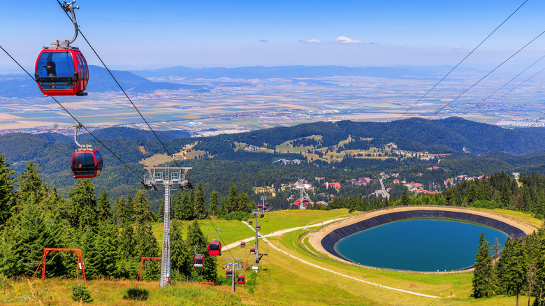 Shot of numerous lifts carrying people up a green mountainside in Brașov, Romania