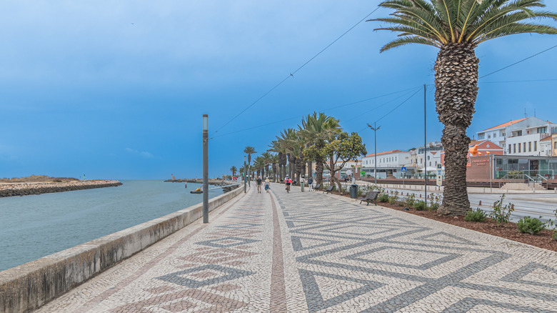 People walking on a stone pathway near the port in Lagos, Portugal