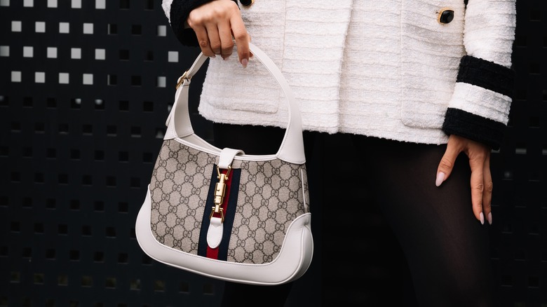 Stylish woman holding Gucci Jackie bag