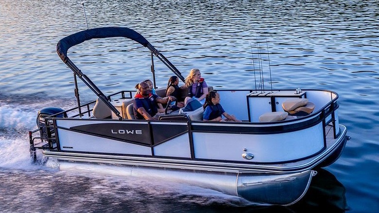 A group of adults and children riding on a Lowe LF 194 as the sun sets