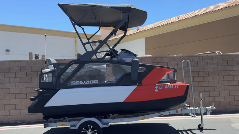 A red Sea-Doo Switch Compact on a trailer in front of a brick fence