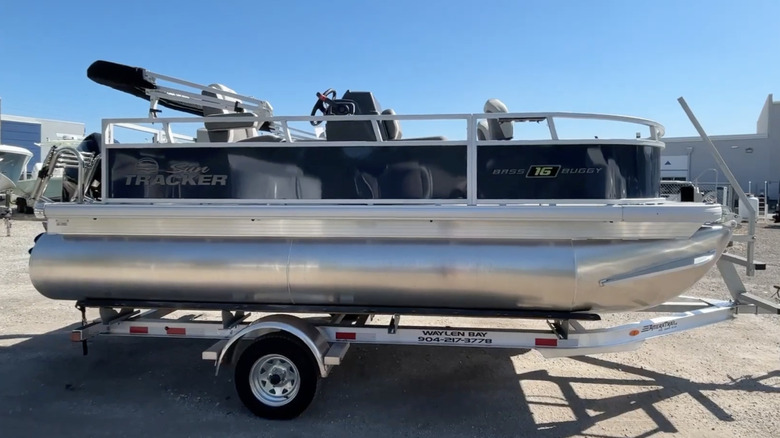 A sideview of a Sun Tracker Bass Buggy 16 XL Select on a trailer in a marina parking lot