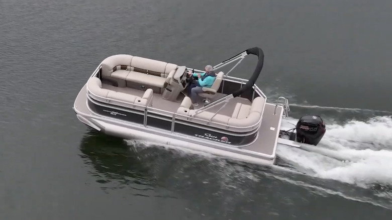 Lone man steering a Sun Tracker Party Barge 20 DLX on a lake