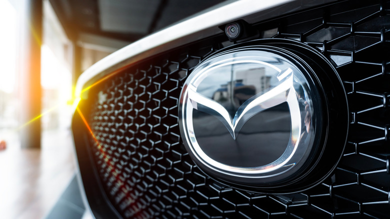 The Mazda logo on the front of a grey vehicle.