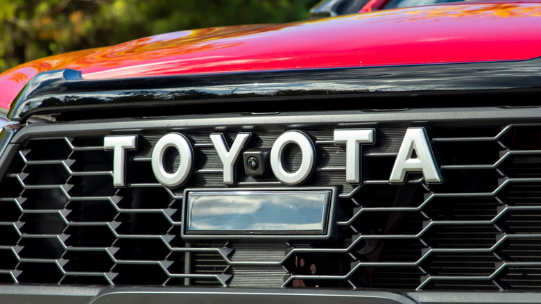 The Toyota logo on the grill of a red vehicle.