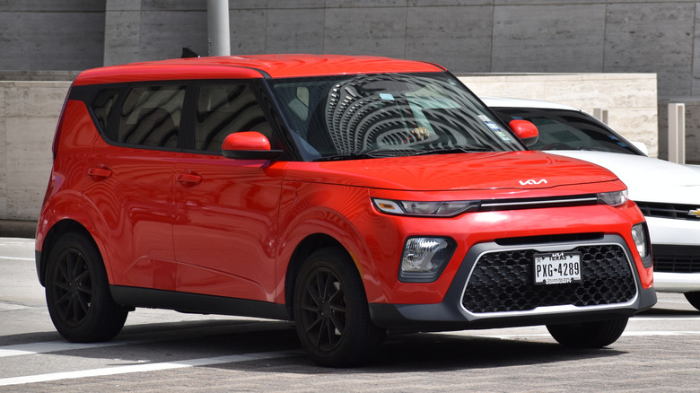 A red 2021 Kia Soul parked beside a white Chevrolet Camaro