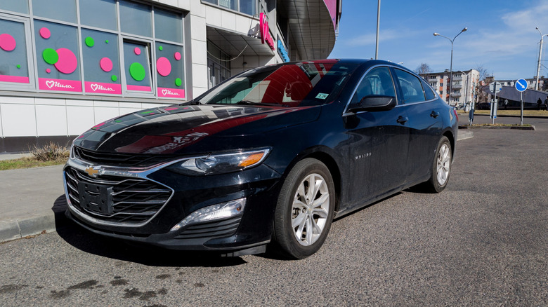 A black Chevrolet Malibu parked along a curb in a city