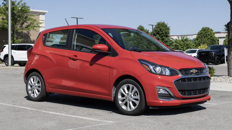 A red used Chevrolet Spark in a parking lot on a sunny day