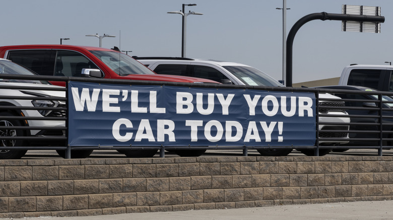 "WE'LL BUY YOUR CAR TODAY!" sign at a car dealer.