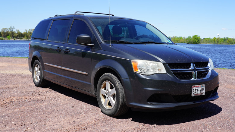 Dark gray Dodge Grand Caravan parked in a nature setting.