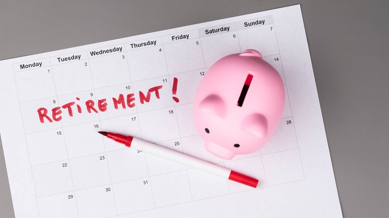 A calendar with the word retirement written on it under a pen and piggie bank