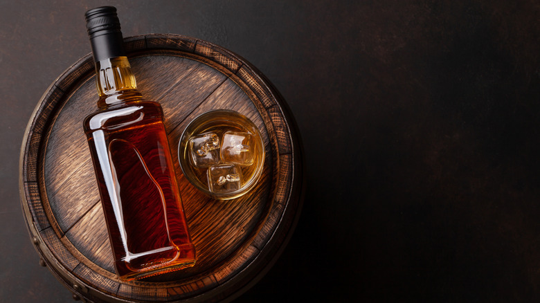 A bottle of whiskey on a whiskey cask.