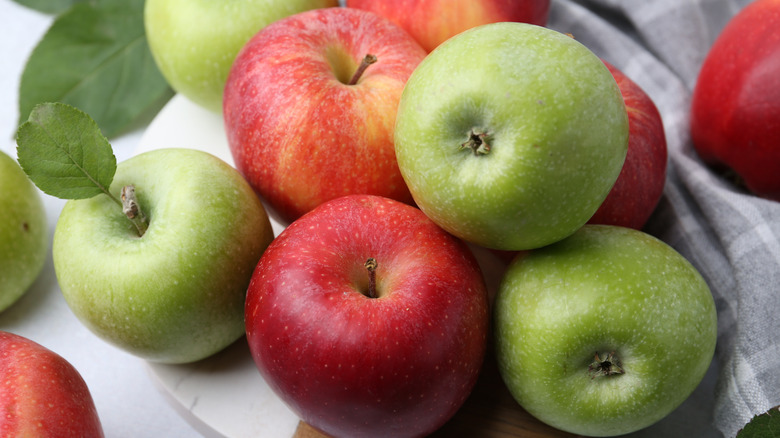 A pile of various types of apples on a tray