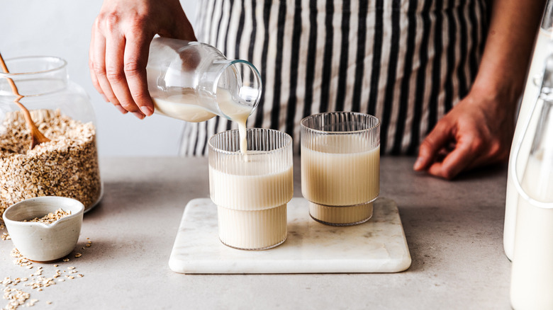 A woman pours milk into glasses