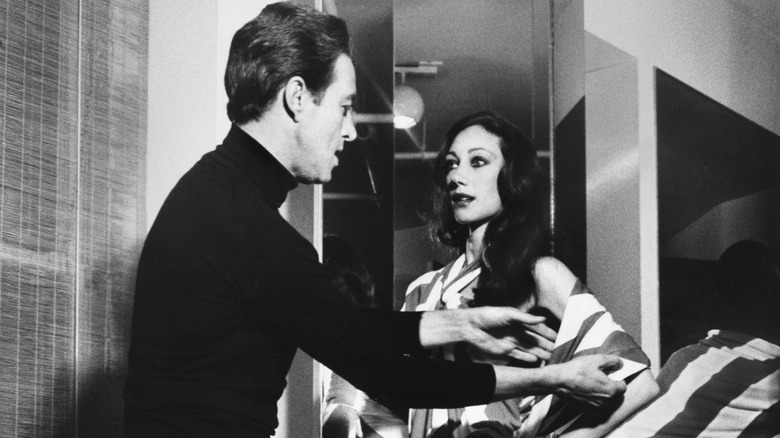 Black and white photo of man measuring female model in front of a mirror