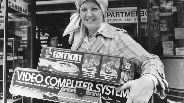 photo of woman in front of store holding Simon game and video game console