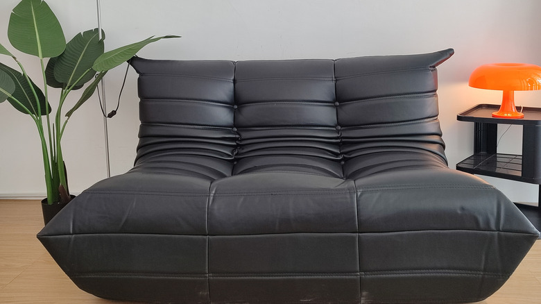 Togo chair in minimalist room with plant and orange lamp