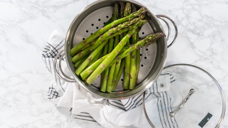 Top view of asparagus inside a steamer resting on a towel and kitchen counter top