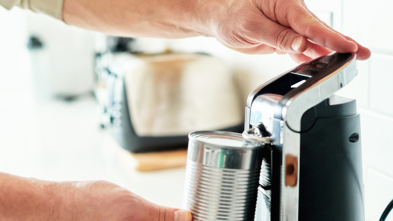 A man operates an electrical can opener