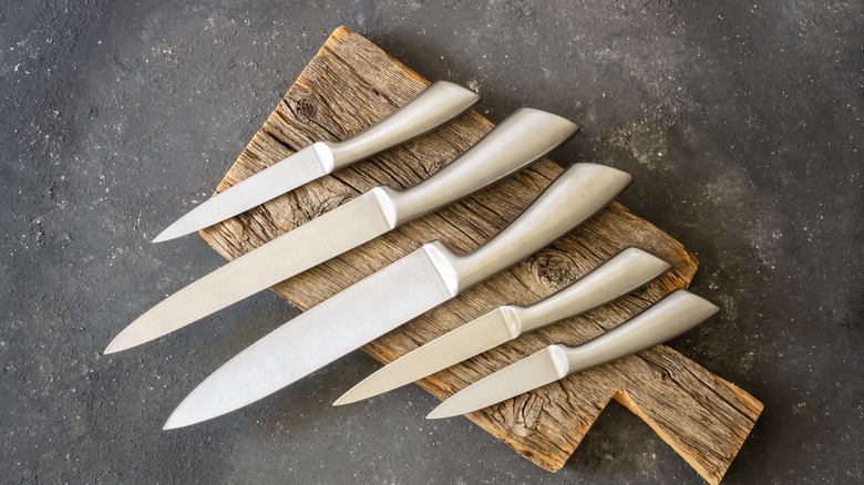 A set of five sharp kitchen knives on a wooden cutting board