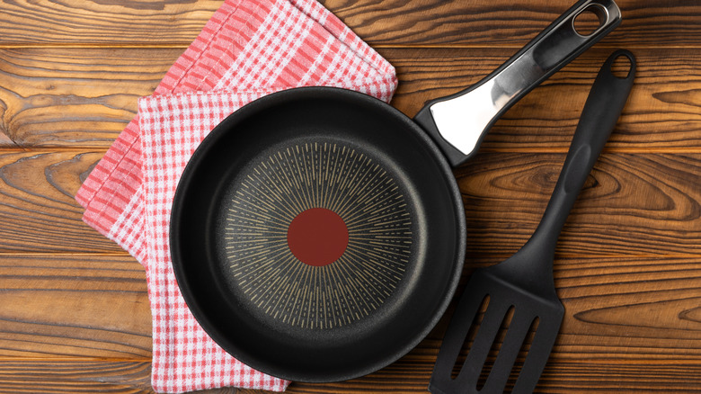 Top view of non-stick pan sitting o towel next to plastic spatula