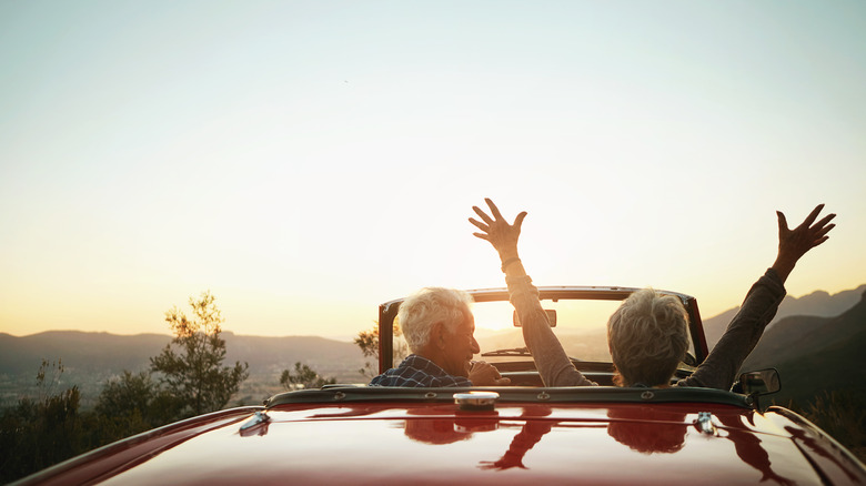 retirees driving into the sunset in a car