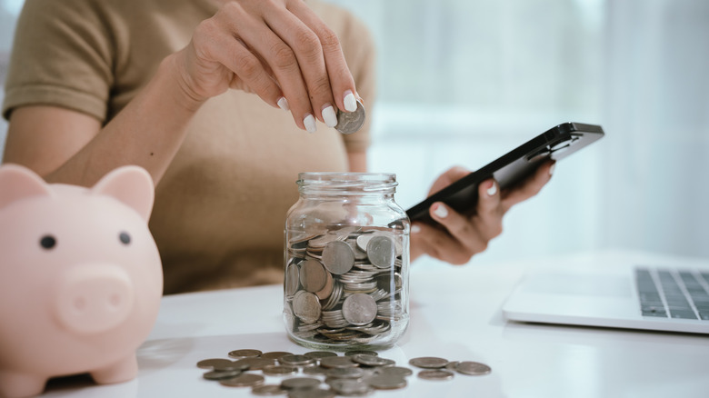hand putting coins in a jar