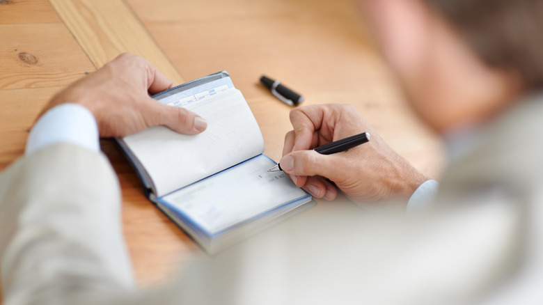 person writing in their checkbook