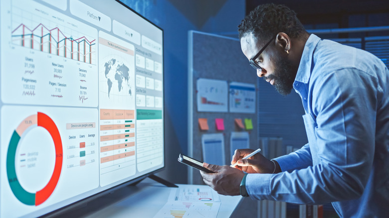 man working near a screen filled with charts