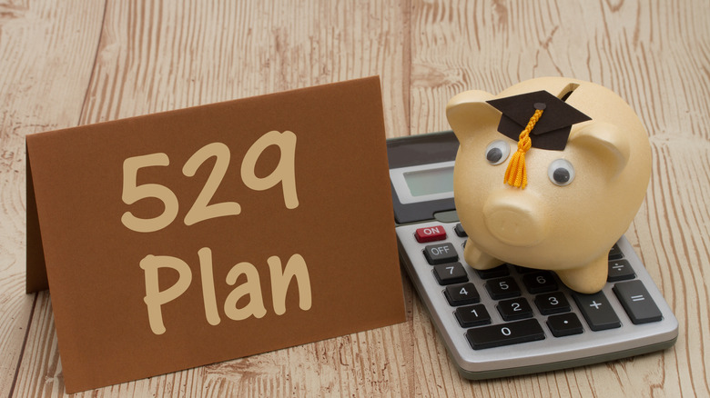 "529 plan" sign and a piggy bank wearing a graduation cap on top of a calculator