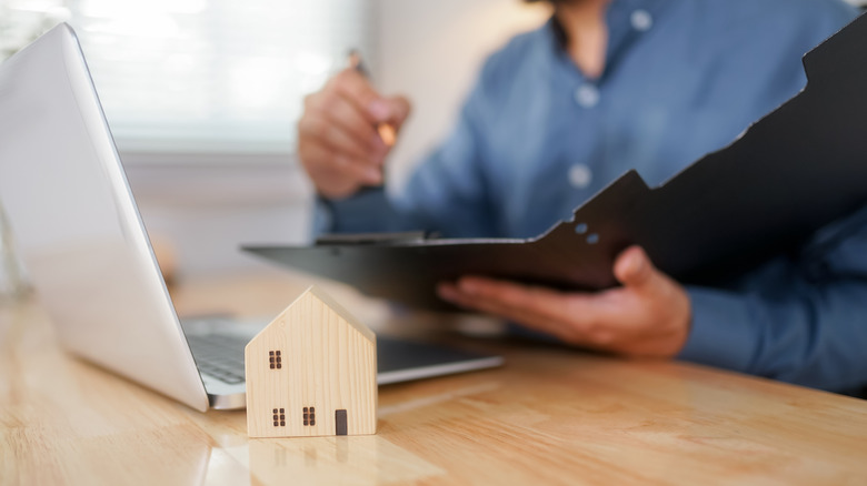young adult looking at laptop next to house figurine