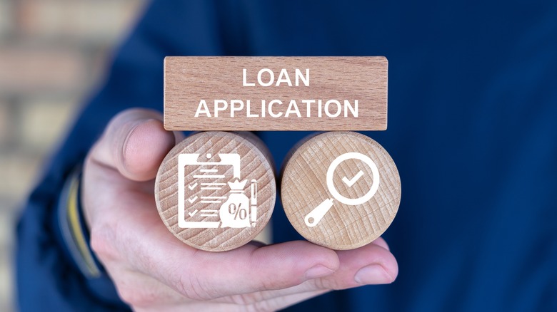 Person holding wooden blocks with icons sees the words LOAN APPLICATION.