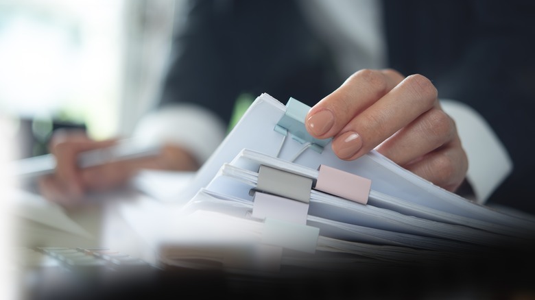 Businesswoman working with stack of paper files to signify complication.