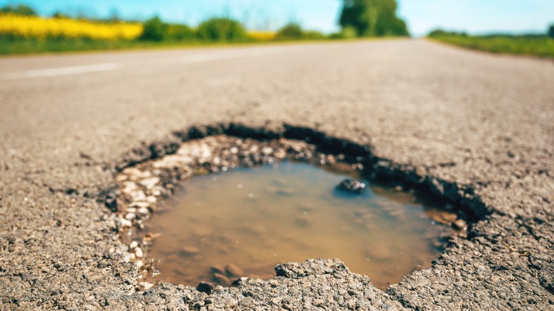 Close up of massive pothole filled with water
