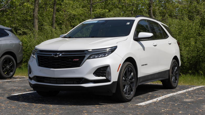 A white 2022 Chevrolet Equinox parked in front of a tree line