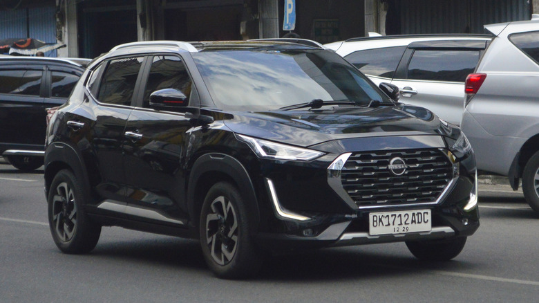 A black 2022 Nissan Kicks driving past parked cars