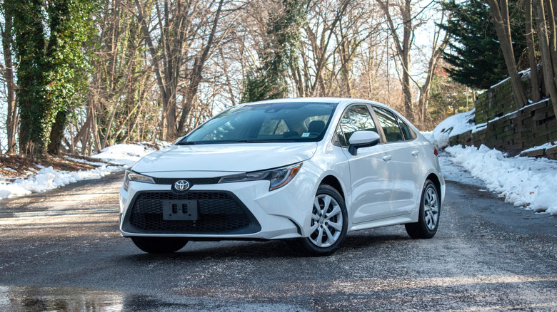 A white Toyota Corolla in the winter time with snow.