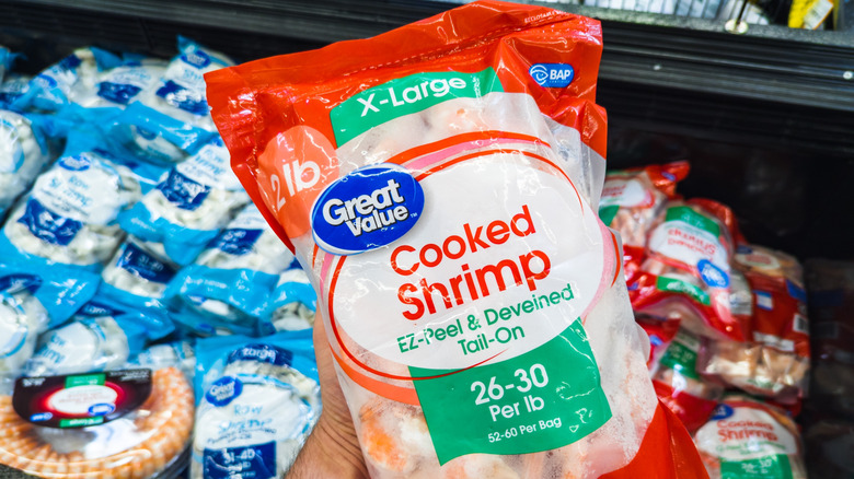 Hand holding a package of Walmart store brand shrimp