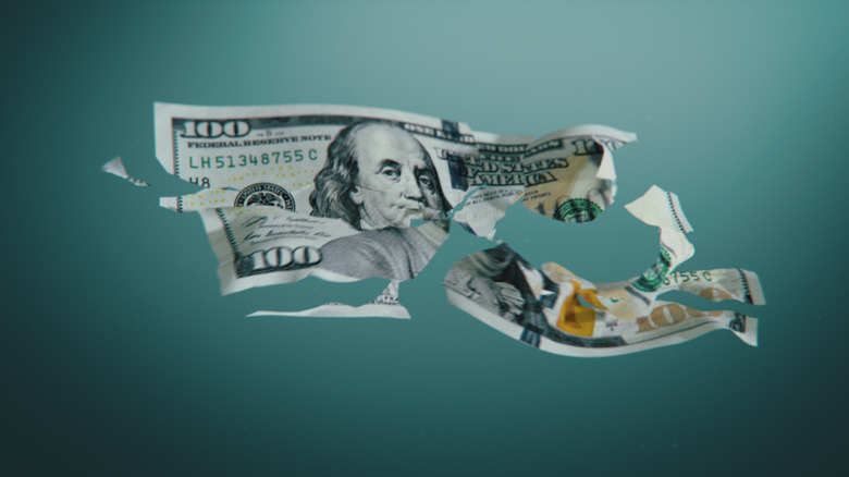 a ripped $100 bill floats in the air