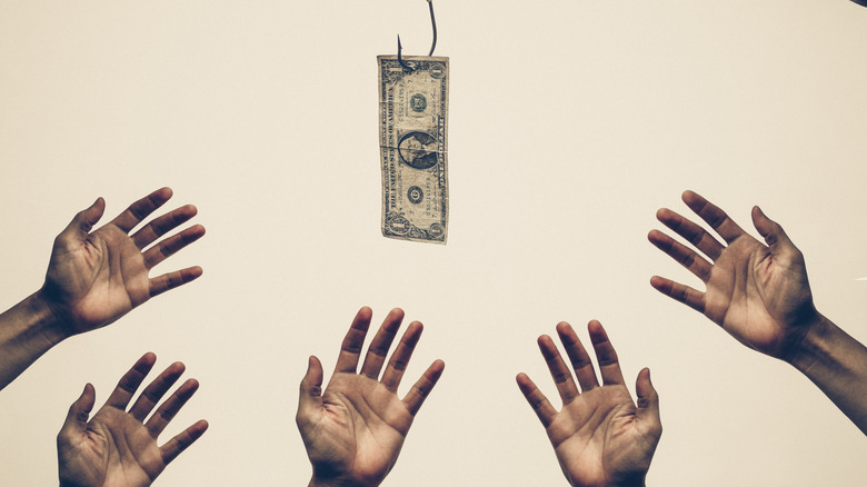 five hands reaching for a dollar bill dangling from a hook