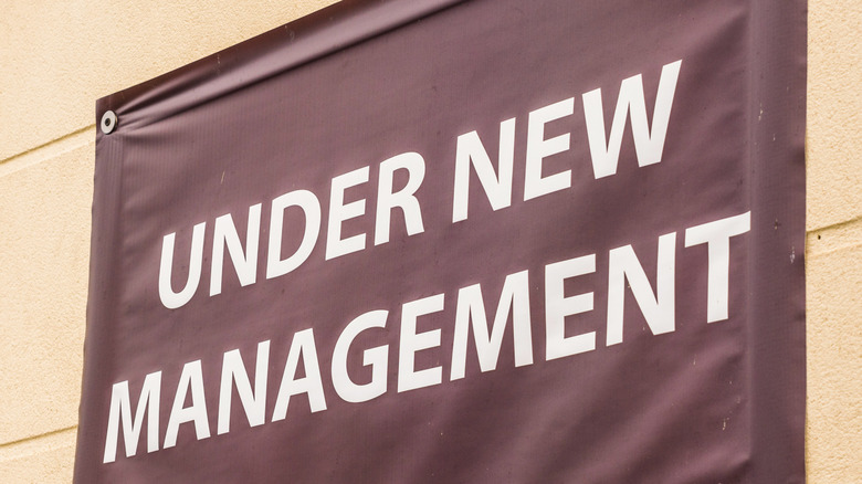 sign posted to exterior wall reading: New Management