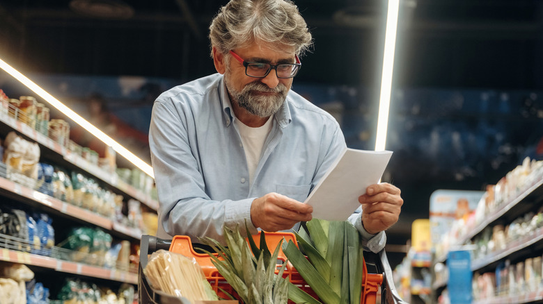 man looking at grocery list  in supermarket