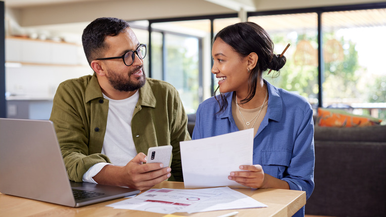 couple checking finances with laptop and papers inside home