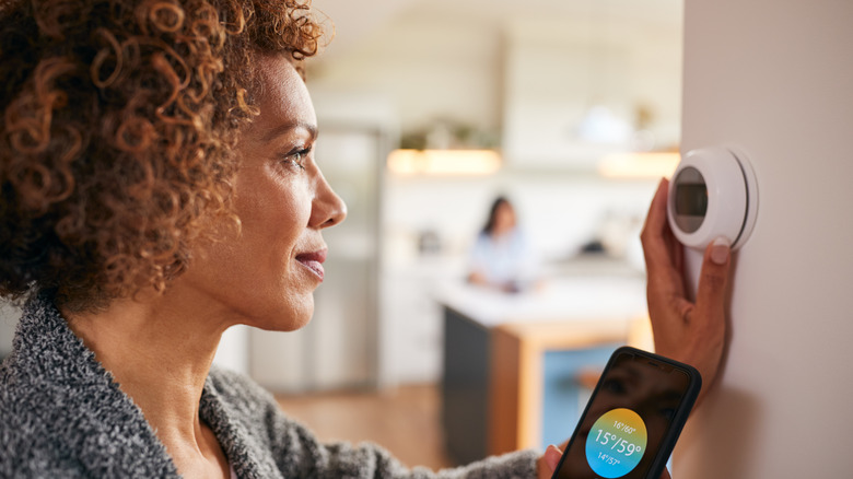A woman using an app on phone to check thermostat