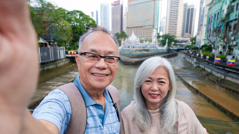 Mature couple on boat take picture of themselves with skyscrappers in background