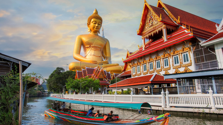 Large seated Buddha statue next to a Thai temple