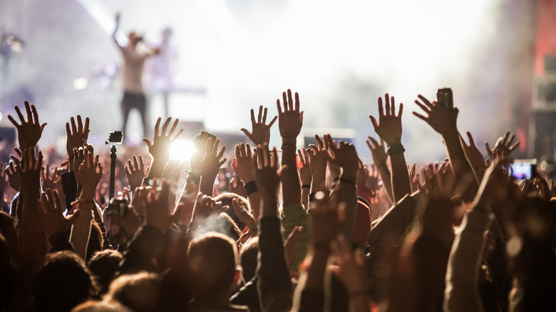 Many hands raised in the air as people attend a concert